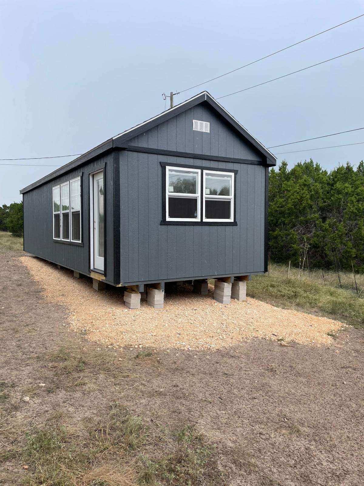Gray Alamo Series shed showing its A-frame roof, house-style door, and windows