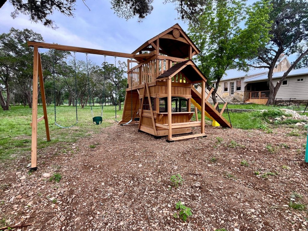 Playset and swing beam installed level on a rocky, sloped Hill Country yard