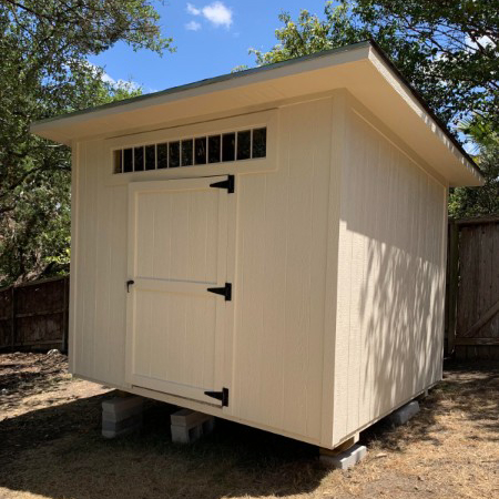 Light-colored Studio Shed with double doors and a transom window