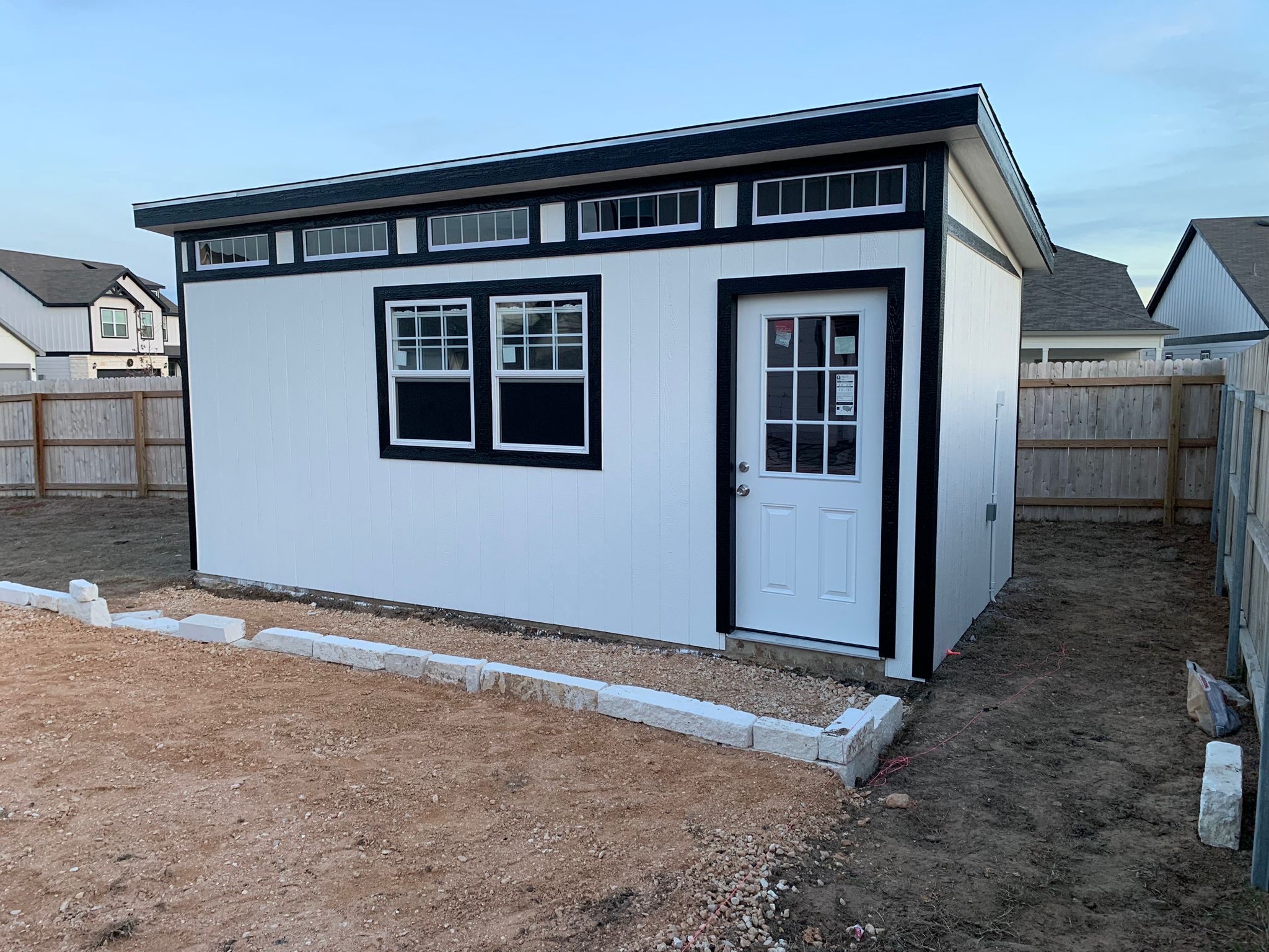 Wide Studio Shed with white siding, black trim, and high windows