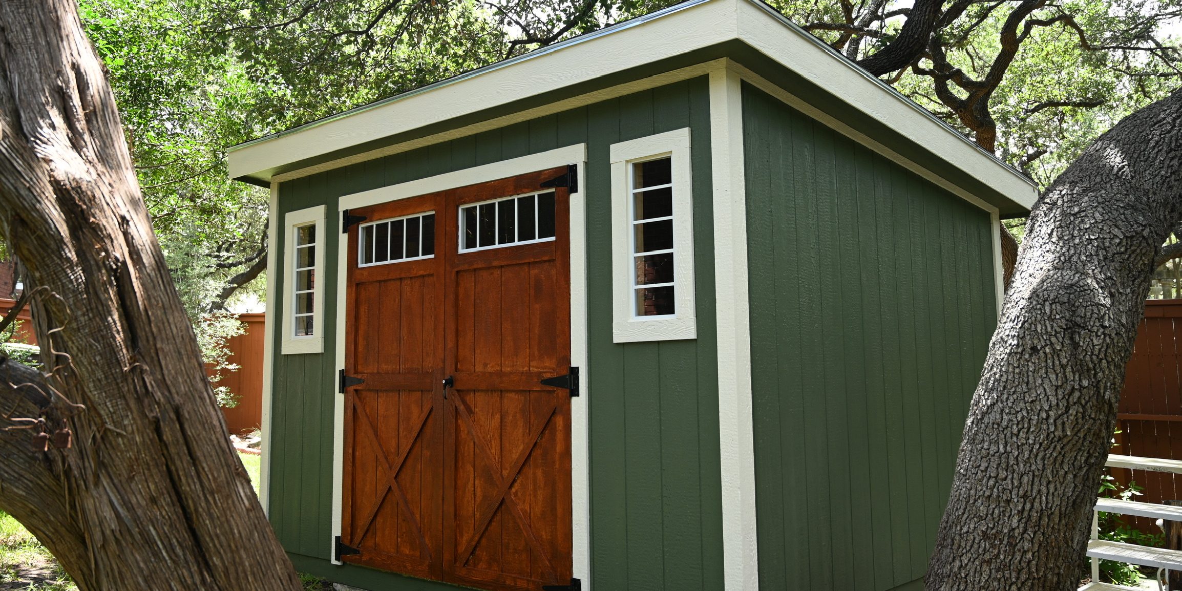 Green Studio Shed with white trim and natural wood double doors